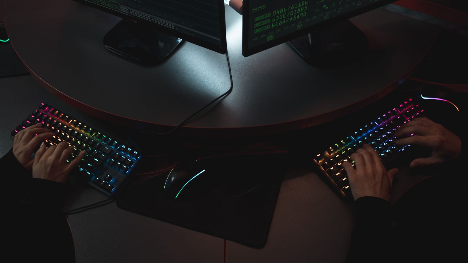 Two people working at keyboards beside security monitoring screens