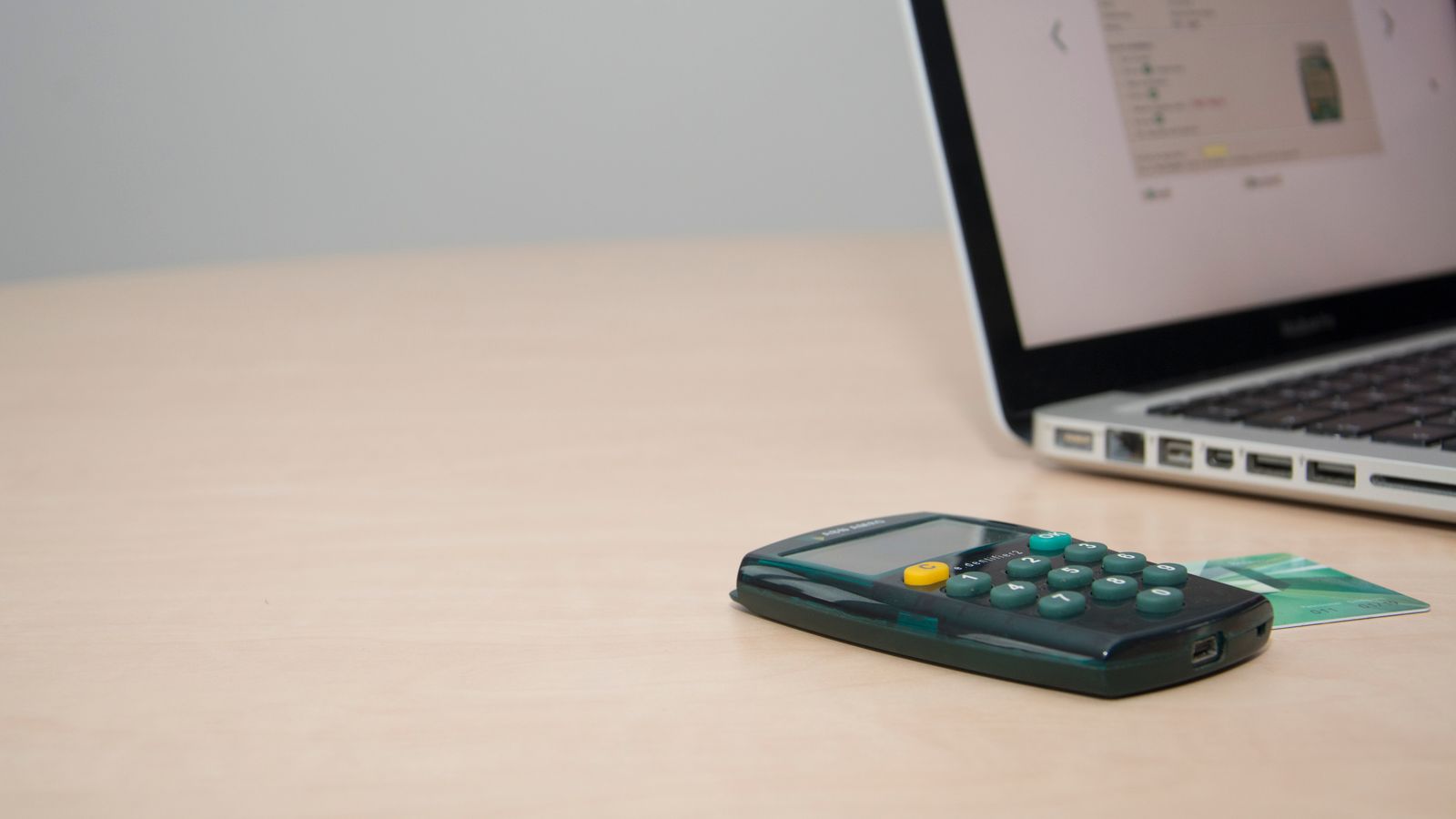 Calculator, payment card, and laptop on a desk